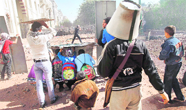 An Egyptian protester wears a bucket on his head for protection as fellow demonstrators take cover during clashes with the police in Cairo on Sunday.