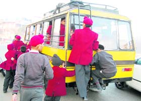 Students cling on to the stairs of a school bus in Amritsar