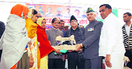 Former Union Minister Anil Shastri presents a sewing machine to war widows in Rewari.