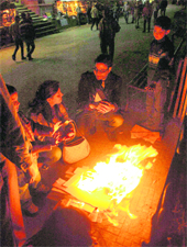 People warm themselves near a fire in Shimla as the mercury dipped on Monday. 