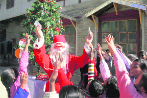 A man dressed as Santa Claus distributes candies among children in Shimla.