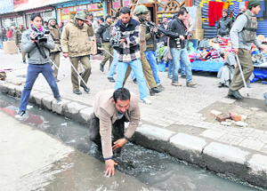 A teacher falls into an open drain after being chased by the police during a protest in Srinagar on Tuesday.