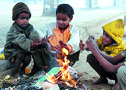 Children keep themselves warm by lighting a fire to brave the cold wave conditions