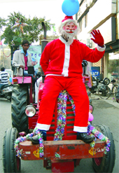A man dressed as Santa Claus rides a tractor during a procession organised in Jalandhar on Thursday .
