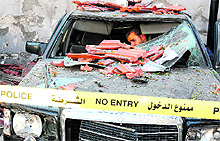 A security personnel inspects a wrecked car in the parking lot of the Syrian General Intelligence headquarters in Damascus on Friday