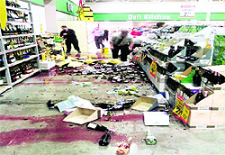 Post-quake, staff at a Christchurch supermarket clean up smashed wine bottles on Friday