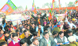 BJP supporters raise party flags; and (below) disposable glasses littered all around the rally venue on Rama Mandi-Hoshiarpur Road in Jalandhar on Saturday. 