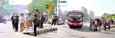 People standing on a footpath near the Bharat Nagar Chowk and boarding the bus in the absence of a shelter.
