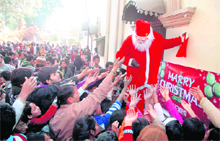 A Santa Claus distributes sweets among people at St Francis Church on Christmas in Dehradun on Sunday.