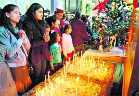 Devotees offer prayers after lighting candles on Christmas at the historical Christ Church in Shimla on Sunday