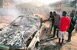 Men look at the wreckage of a car following a bomb blast at St Theresa Catholic Church outside the Nigerian capital Abuja on Sunday