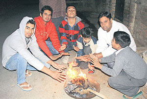 People sit around a bonfire on a cold night in Rohtak. 