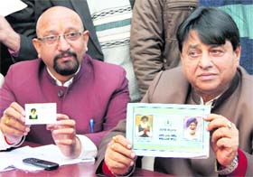 District Congress president Arun Walia along with a DCC member shows the copy of a vehicle registration certificate and a blue card bearing pictures of CM Parkash Singh Badal and minister Adesh Partap Singh Kairon in voilation of the model code of conduct in Jalandhar on Monday