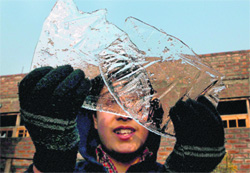 A teenager looks through sheets of ice in Srinagar on Monday