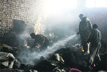 Fire department officials douse flames at a factory in Ludhiana on Monday.