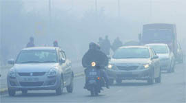 Commuters move on a road amid a blanket of fog. Fog and cold conditions have made the life hard for the people in the Capital. 