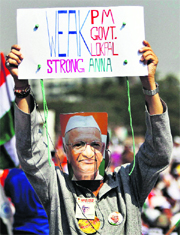 A man in a Hazare mask holds up a placard on the first day of his fast at MMRDA grounds in Mumbai.