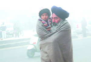A man wraps his child in a shawl to protect him from the severe cold in Bathinda on Wednesday morning. 