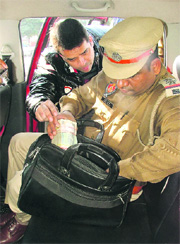 A policeman searches a bag containing unaccounted cash in Ludhiana on Wednesday