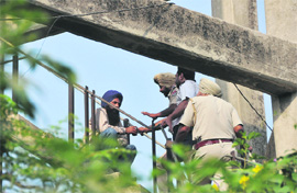 Policemen try to convince an NRHM employee sitting atop a water tank. a file photo