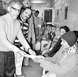 Arvind Kumar, joint director finance, gives cash payment to Raghunath, an accident victim, at ESIC Hospital in Chandigarh on Thursday.