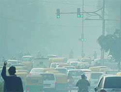 Traffic passes through a thick blanket of fog on a chilly morning in New Delhi on Thursday