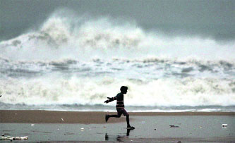 A boy plays on the Marina beach in Chennai with high-rising waves in the background on Thursday.