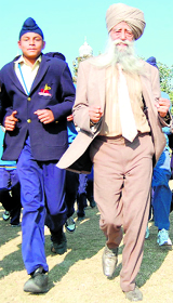 Centenarian marathoner Sardar Fauja Singh runs with school students during a visit to Amritsar on Friday.