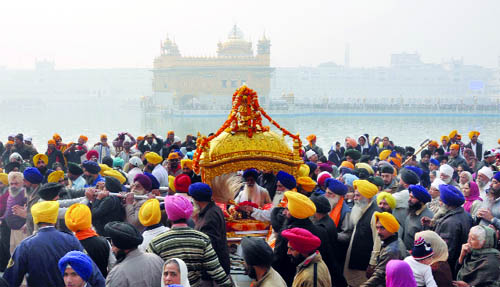 Devotees carry a palanquin during a nagar kirtan at the Golden Temple on the eve of the birth anniversary of Guru Gobind Singh in Amritsar on Friday. 