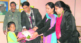 Ravinder Sharma, Member Legislative Council, and Congress spokesperson, gives away warm clothes to a child in Jammu.