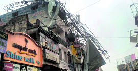 A massive hoarding perched precariously atop a building after Cyclone Thane battered Puducherry, on Saturday.