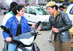 A woman cop offers flowers to an underage two- wheeler rider in Sirsa