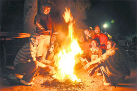 With the temperature nosediving in the region, people sit around a bonfire to catch some warmth on a chilly evening in Karnal. 