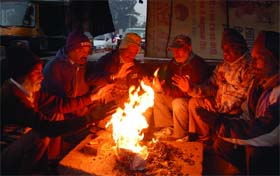 People sit by a bonfire near the railway station in Jalandhar on Sunday