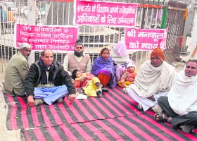 Handicapped Manphool Singh (wearing monkey cap) along with members of his family stages a dharna at Ambedkar Chowk in Jhajjar on Monday