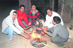 As the mercury dips, people sit around a bonfire in Lahli village in Rohtak. 