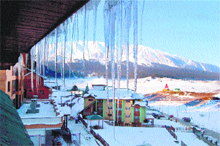 Icicles hang from the rooftop of a buiulding as snow is seen all around the Gulmurg skiing resort on Monday