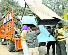 Members of the enforcement wing of the municipal council load material on to a truck during an anti-encroachment drive in Mohali on Tuesday