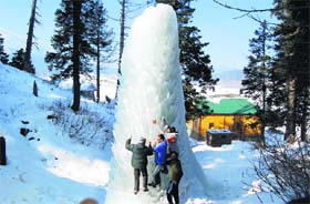 Tourists huddle around a huge ice structure at Gulmarg on Tuesday