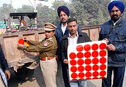 Police personnel paste reflectors on a tractor-trolley as a precautionary measure in view of the foggy weather in Bathinda on Wednesday