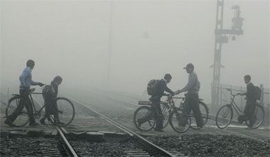 Unmindful of the risk involved, commuters and schoolchildren cross a level crossing on a foggy morning in Jalandhar. 