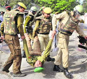 Policemen carry away a protesting Special Police Officer (SPOs) in Guwahati on Wednesday. The SPOs are demanding renewal of their job contracts and clearance of salaries since February 2011. 