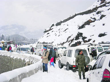 Tourists caught in a fresh spell of snow near Nehru Kund, 5 km from Manali, on the Manali-Rohtang Pass road on Thursday. 