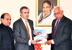 Chief Minister Omar Abdullah along with Deputy Chief Minister Tara Chand presents a publication comprising the achievements of his government to Governor NN Vohra at Raj Bhawan in Jammu on Thursday