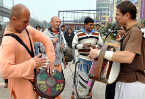 A group of foreigners plays musical instruments and sings bhajans on the roadside in Gurgaon.