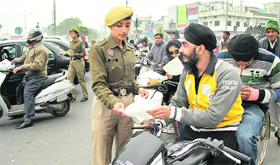 A traffic police personnel distributes pamphlets during the Road Safety Week at Guru Nanak Mission Chowk in Jalandhar on Friday. 