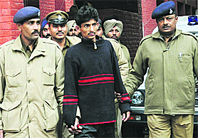Accused Pradeep Joshi (centre) in police custody at Sector 39 police station, Chandigarh, on Saturday.