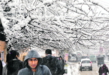 People walk on a Srinagar street during snowfall on Saturday. The cold wave tightened its grip on Jammu and Kashmir with most places in the state recording sub-zero temperatures. 