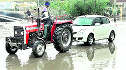 A tractor owner tows away a car stuck in a pool of water in Basti Bawa Khel in Jalandhar on Saturday