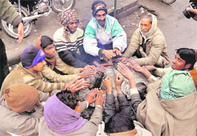 A group of people huddle around a bonfire to keep the chill at bay in Dehradun on Sunday. 
